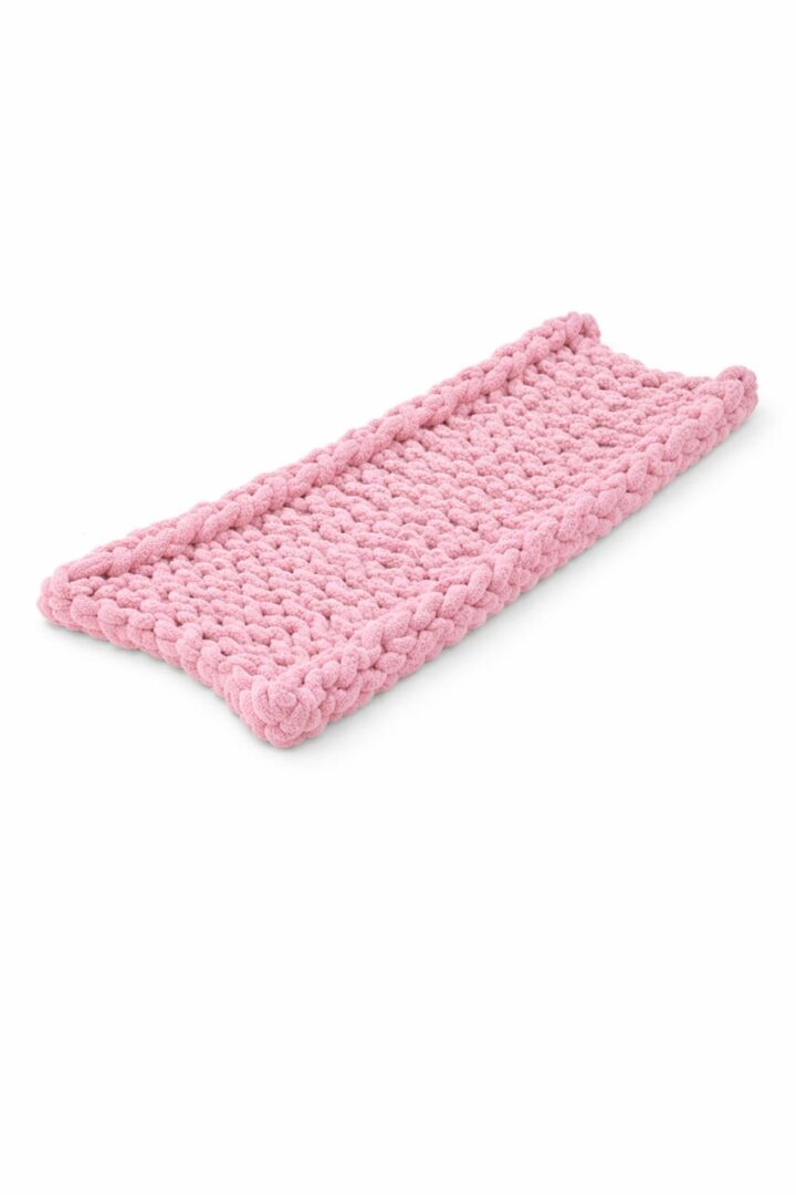 Handmade pink crocheted tray with raised edges.