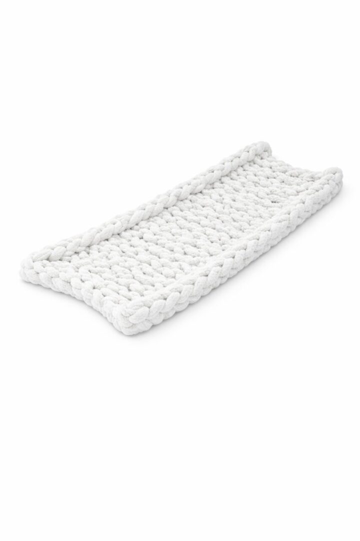 White knitted changing pad with raised edges.